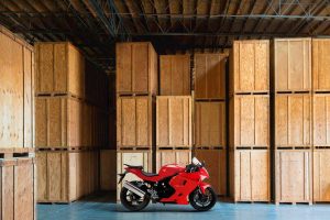 Red motorcycle parked in a warehouse with crated motorcycles in the background