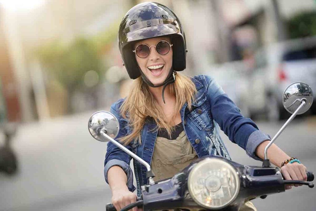 Attractive young woman riding scooter in city center