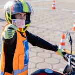 Student driver showing motorcycle driving license as successfully finished riding exams. Concept of motorcycle school of driving.