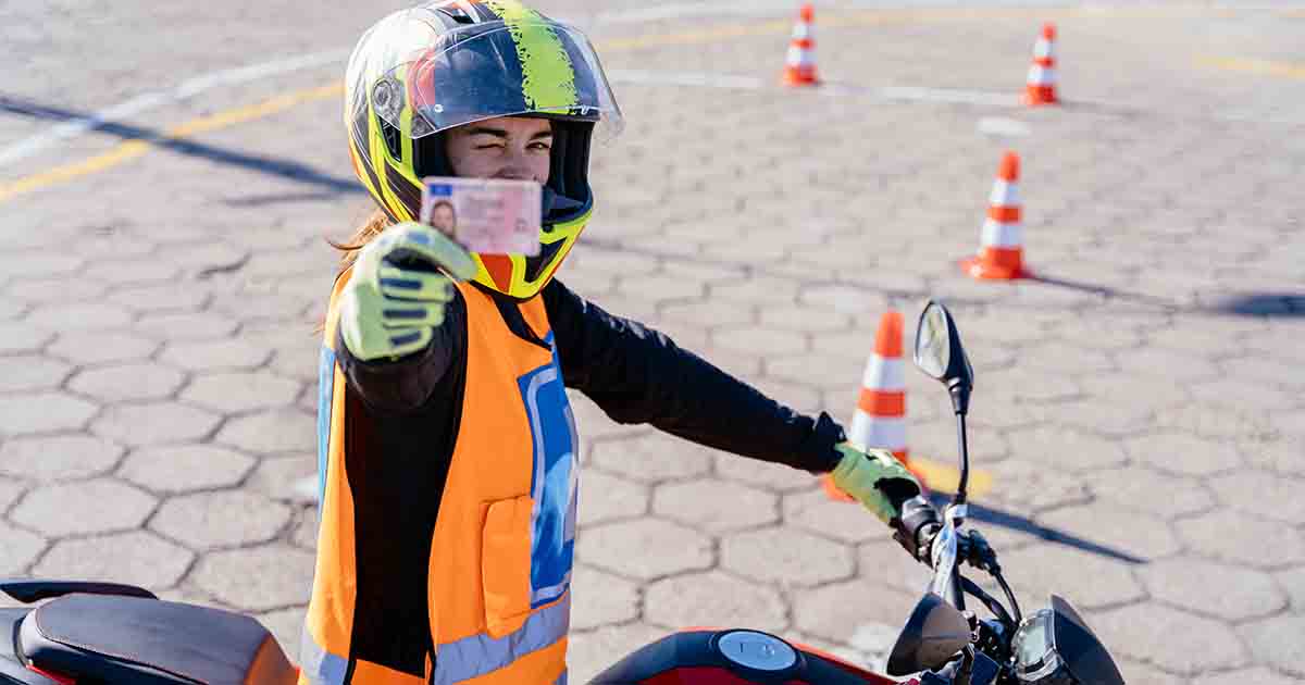 Student driver showing motorcycle driving license as successfully finished riding exams. Concept of motorcycle school of driving.