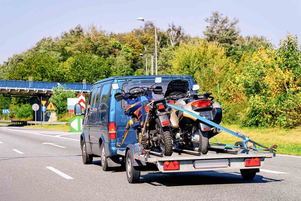 Mini van with motorcycles on trailer in Road.